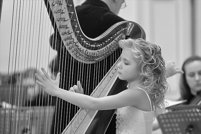 Alisa playing the harp as a young child