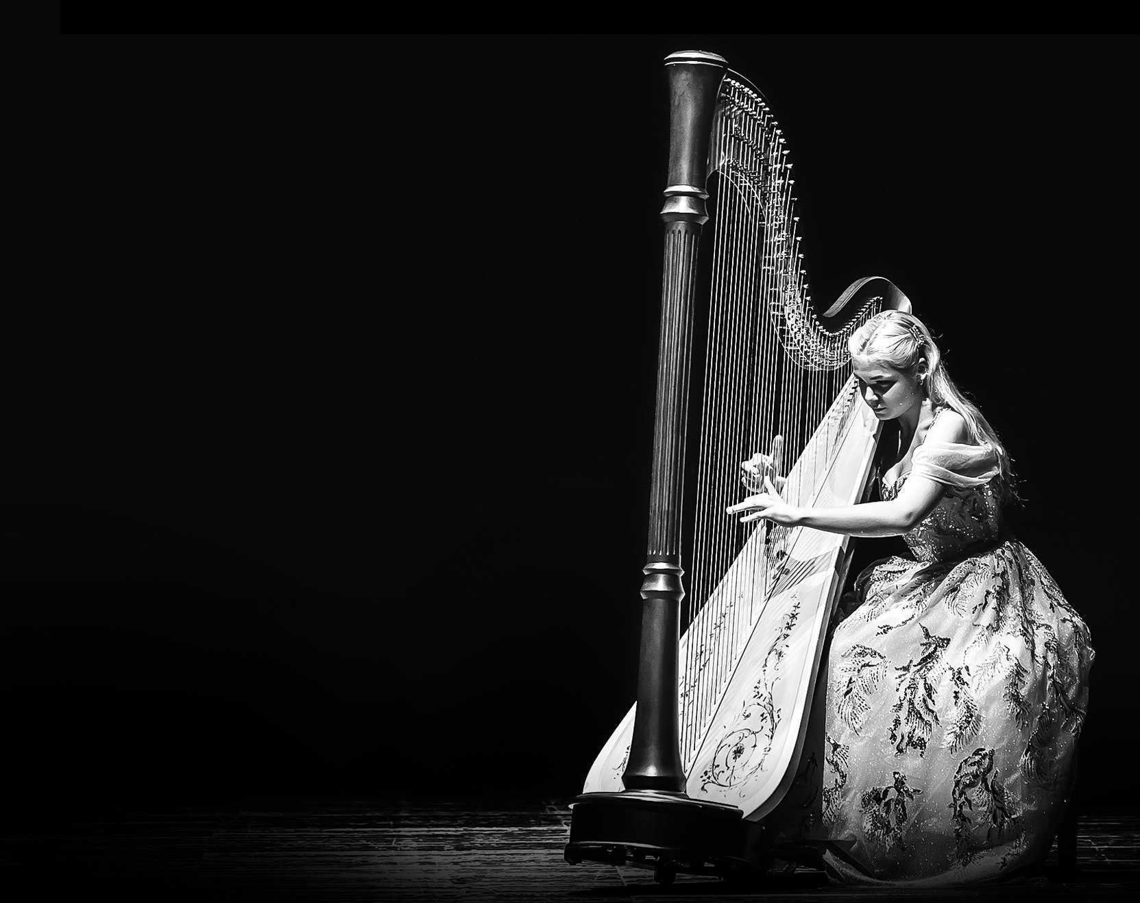 Alisa in a concert gown performing on a grand harp